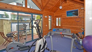A gym with exercise equipment, wooden walls, and large windows. - Dolphin Lodge (Middleton Beach)