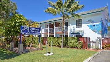 A building with a dolphin mural on the side, a reception sign, and a fenced garden area.