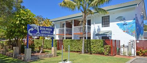 A building with a dolphin mural on the side, a reception sign, and a fenced garden area.