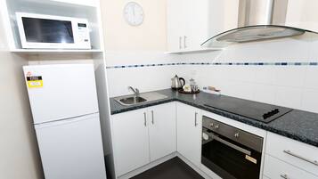A kitchen with white cabinets, a microwave, a stove, and a sink.