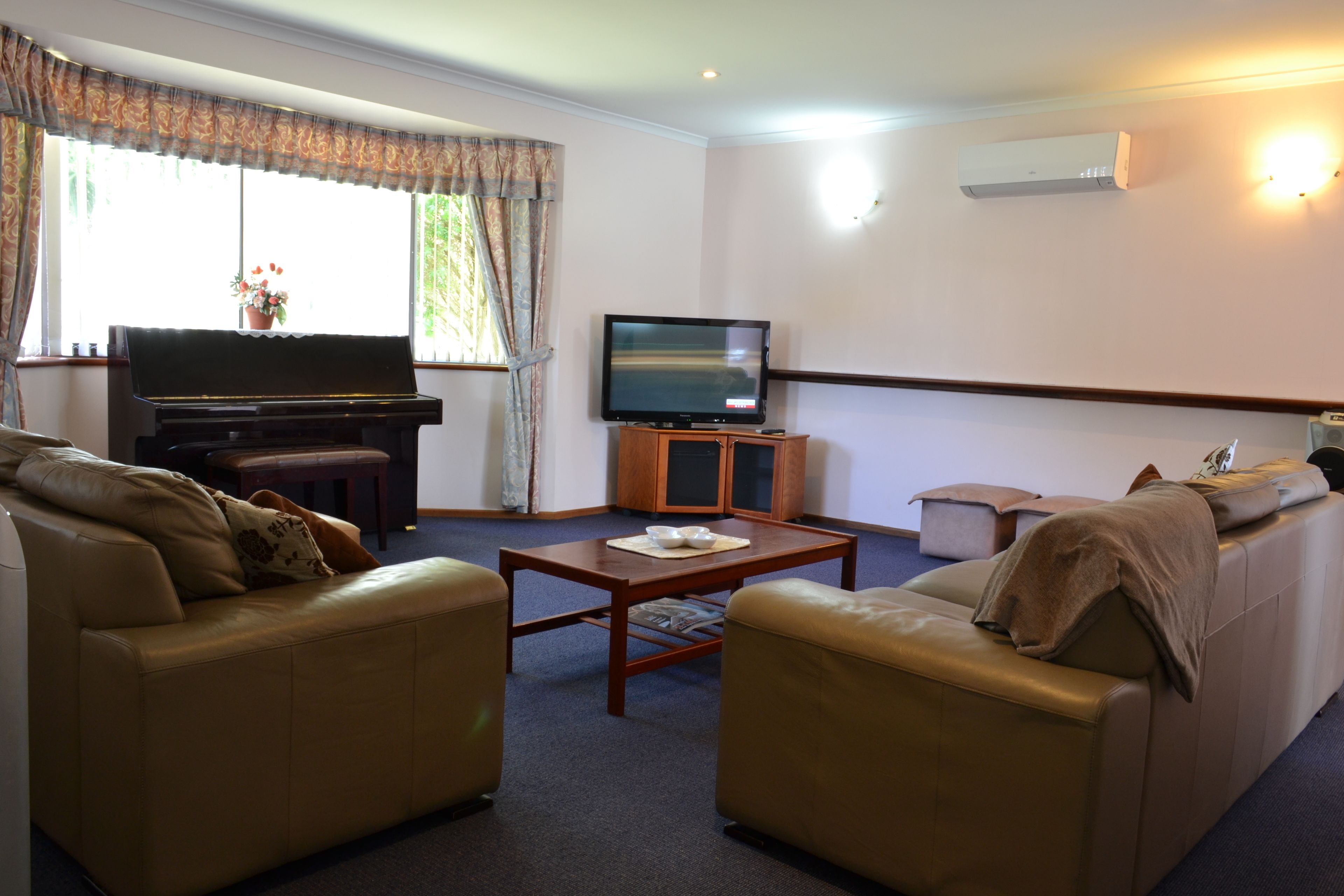 A living room with a piano, television, and two sofas.