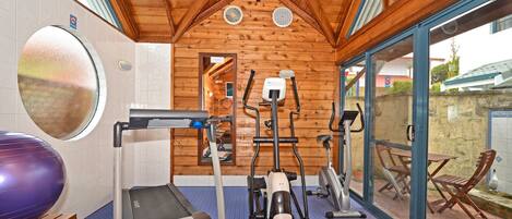 A gym with exercise equipment, a large mirror, and a window overlooking a patio area.