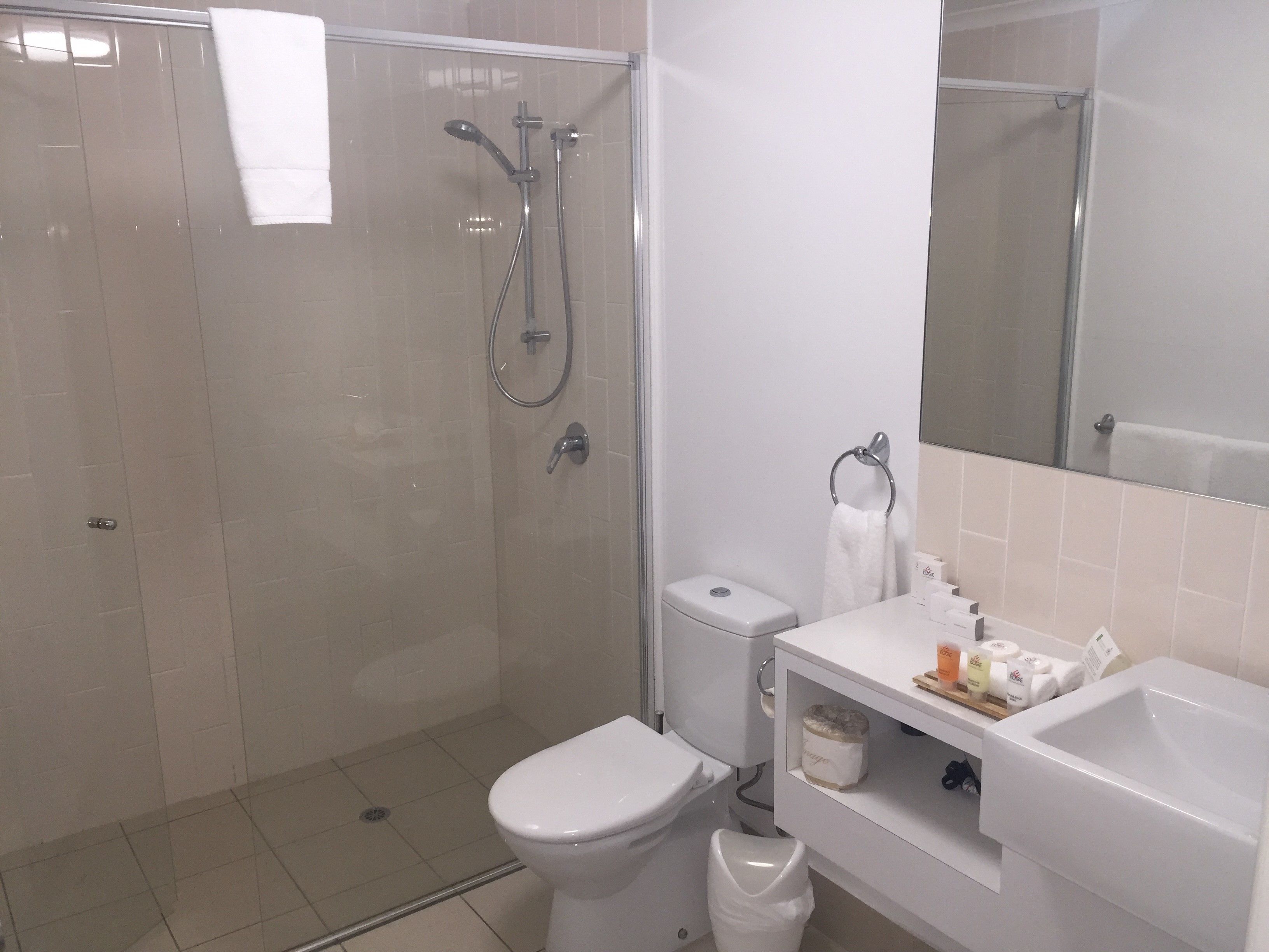 Een moderne badkamer met een douchecabine van glas, toilet en wastafel met toiletartikelen.