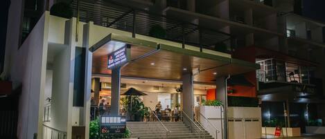 A modern building with a restaurant and bar on the ground floor, featuring a staircase and outdoor seating area.