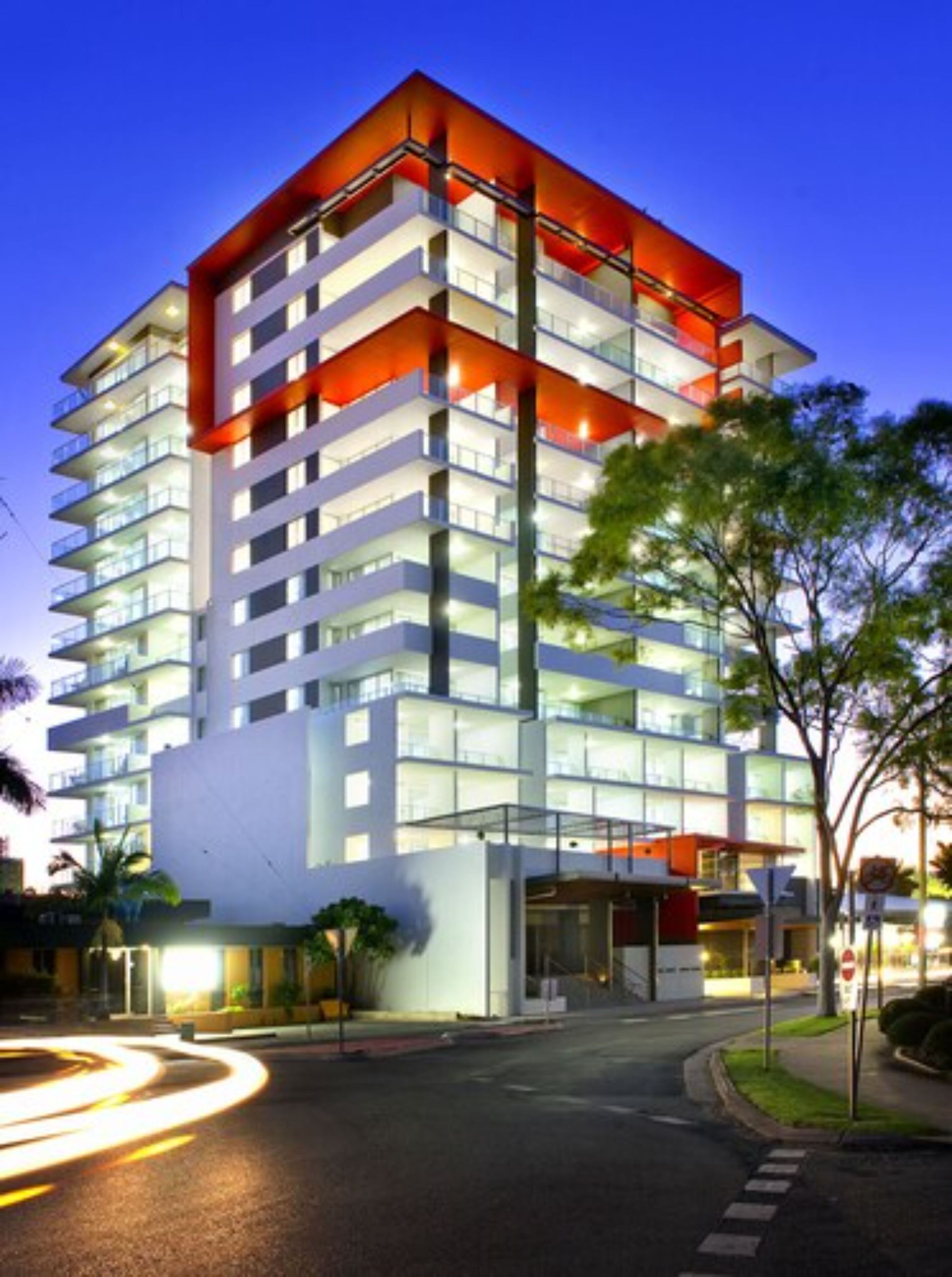 Un hotel moderno de varios pisos con una fachada distintiva en rojo y blanco, grandes ventanales y una zona de entrada bien iluminada.