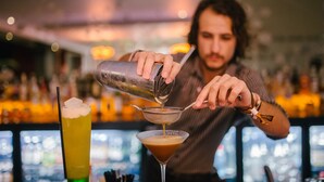 Een barman giet een drankje in een martini glas.