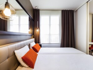 A hotel room with a large bed, a headboard, a mirror, and a window with curtains. - Aparthotel Adagio Marseille Timone (Marseille)