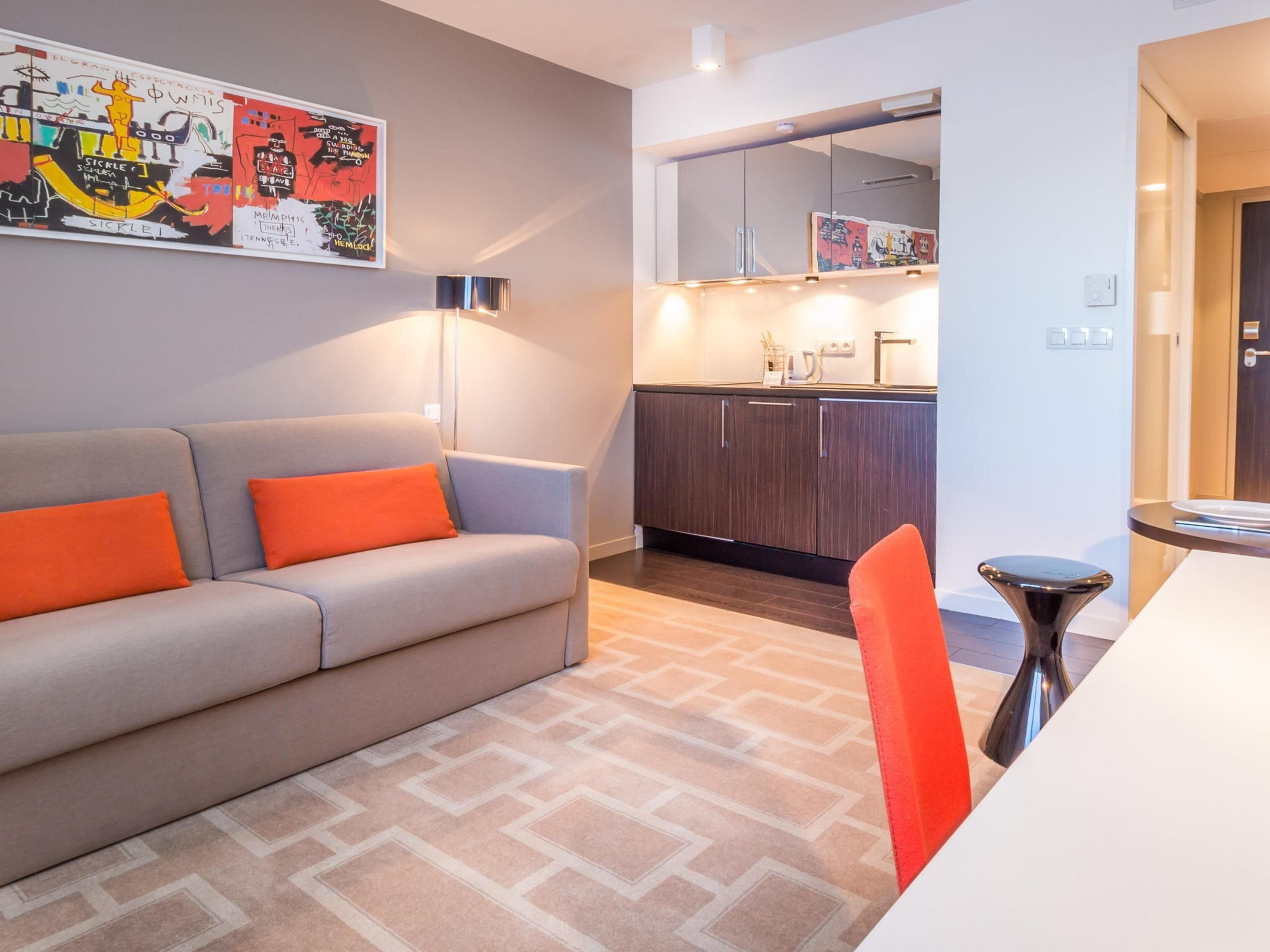Una sala moderna con sofá, mesa de comedor y zona de cocina.