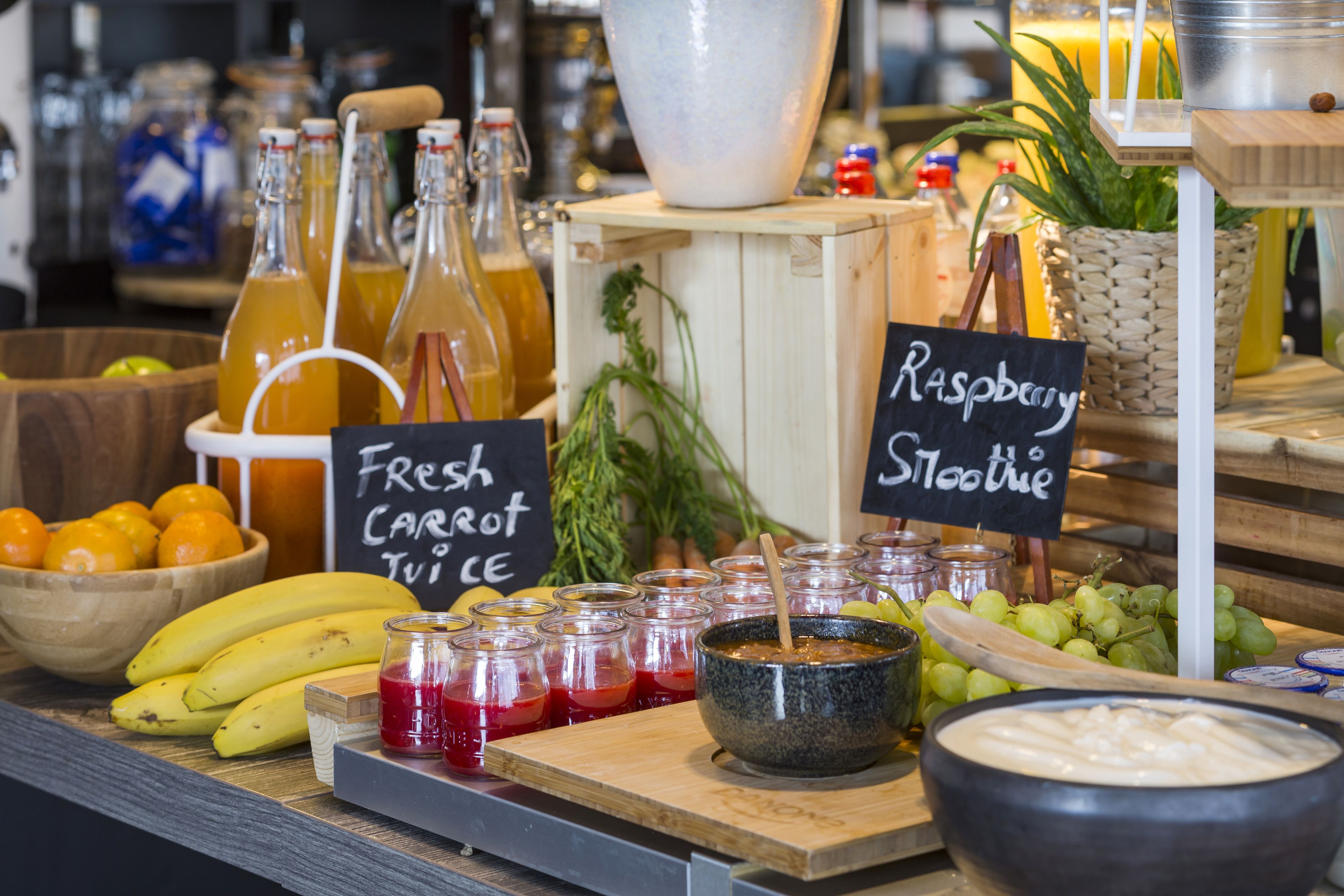 A food display with fresh produce, jars of sauces, and a sign indicating a raspberry smoothie.
