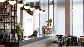 Un espace bar moderne avec un comptoir, des tabourets de bar et des luminaires suspendus.