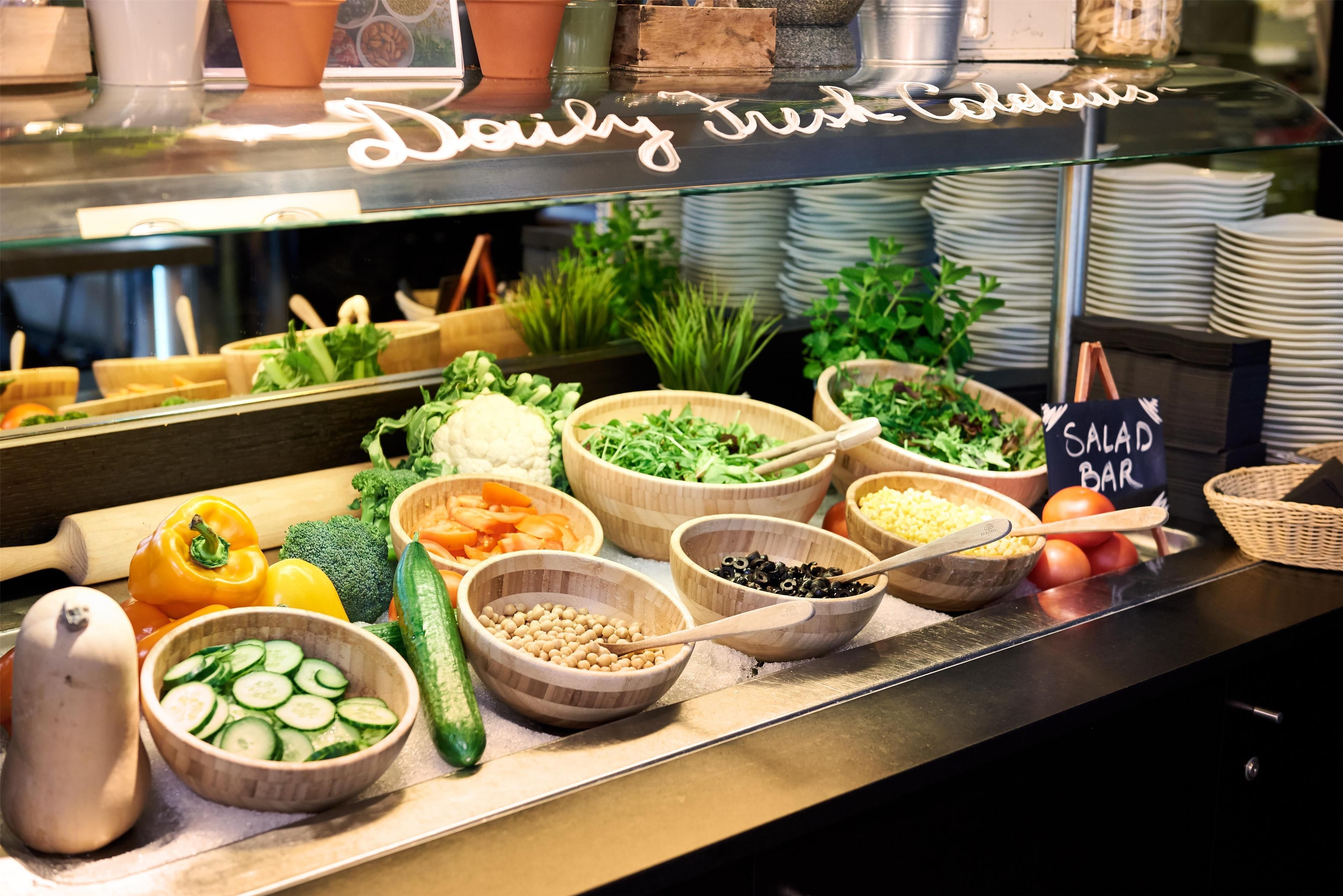 Una barra de ensaladas con diversas verduras y ingredientes frescos.