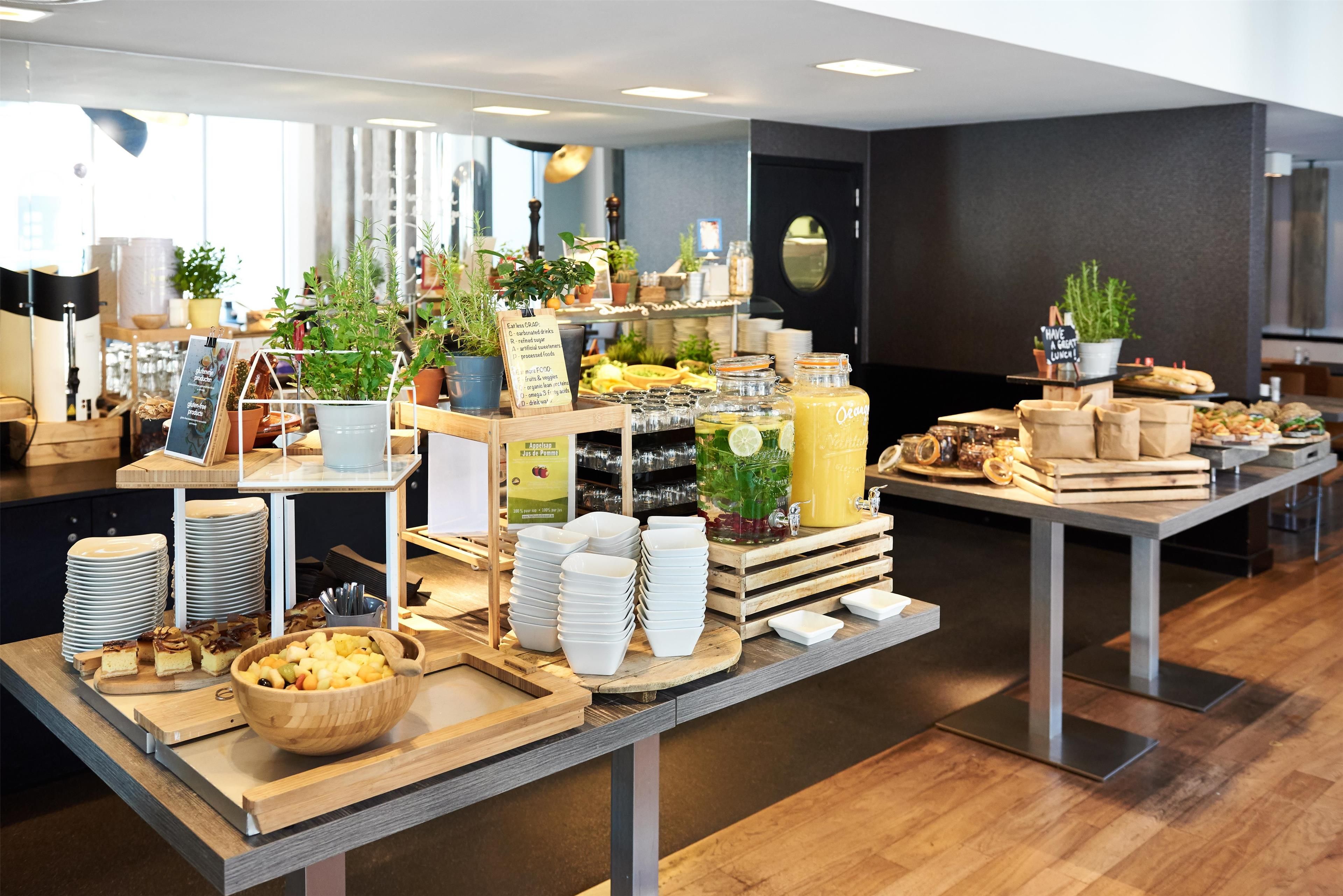 Un'area buffet con diverse portate, distributori di bevande e un cartello che indica prodotti biologici e senza glutine.