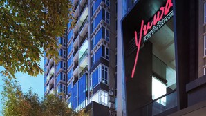 A modern hotel entrance with a prominent sign, a covered walkway, and surrounding greenery. - Yuwa Hotel (Guangzhou)