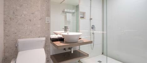 A modern bathroom with a freestanding toilet, a vessel sink, and a glass-enclosed shower area.