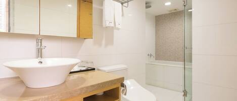 A modern bathroom with a large white sink, a toilet, a glass shower enclosure, and a mirror above the sink.