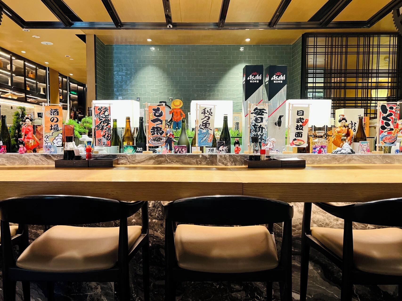 A restaurant with a long counter, chairs, and various Japanese decorations.
