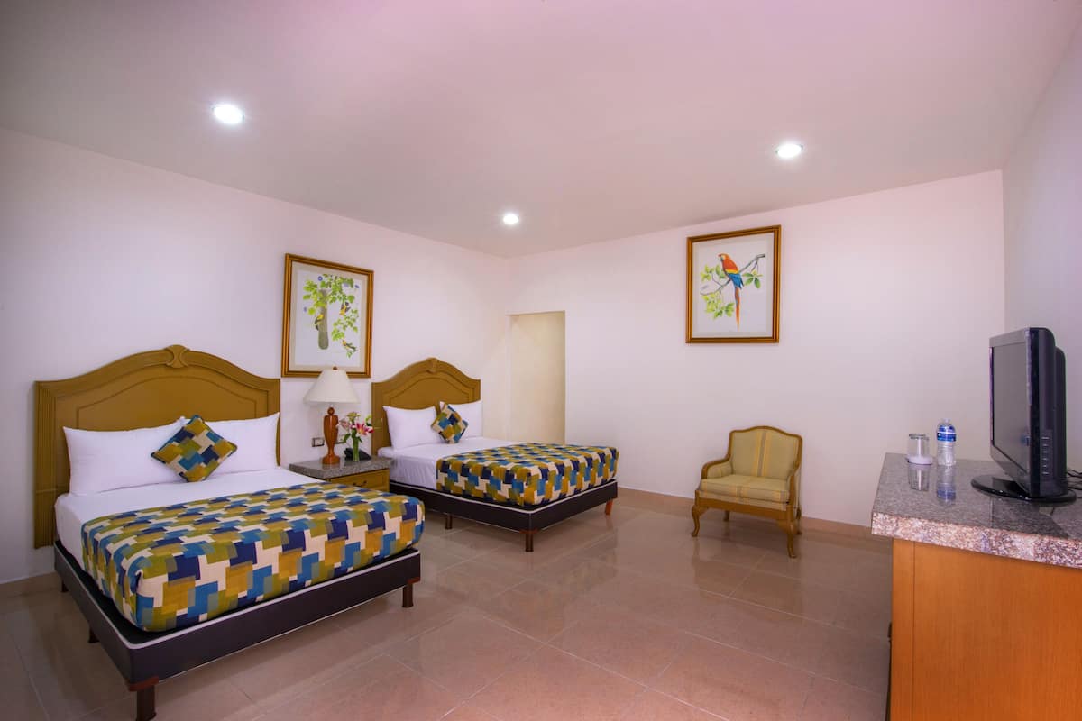 A hotel room with two beds, a television, a chair, and artwork on the walls.