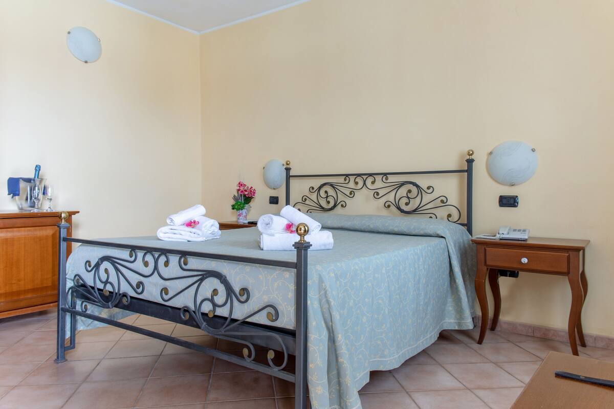 Una camera da letto ordinata con un letto, comodini e una piccola lampada da comodino.