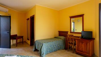 A room with a bed, a desk, a chair, a television on a wooden cabinet, and a mirror on the wall.