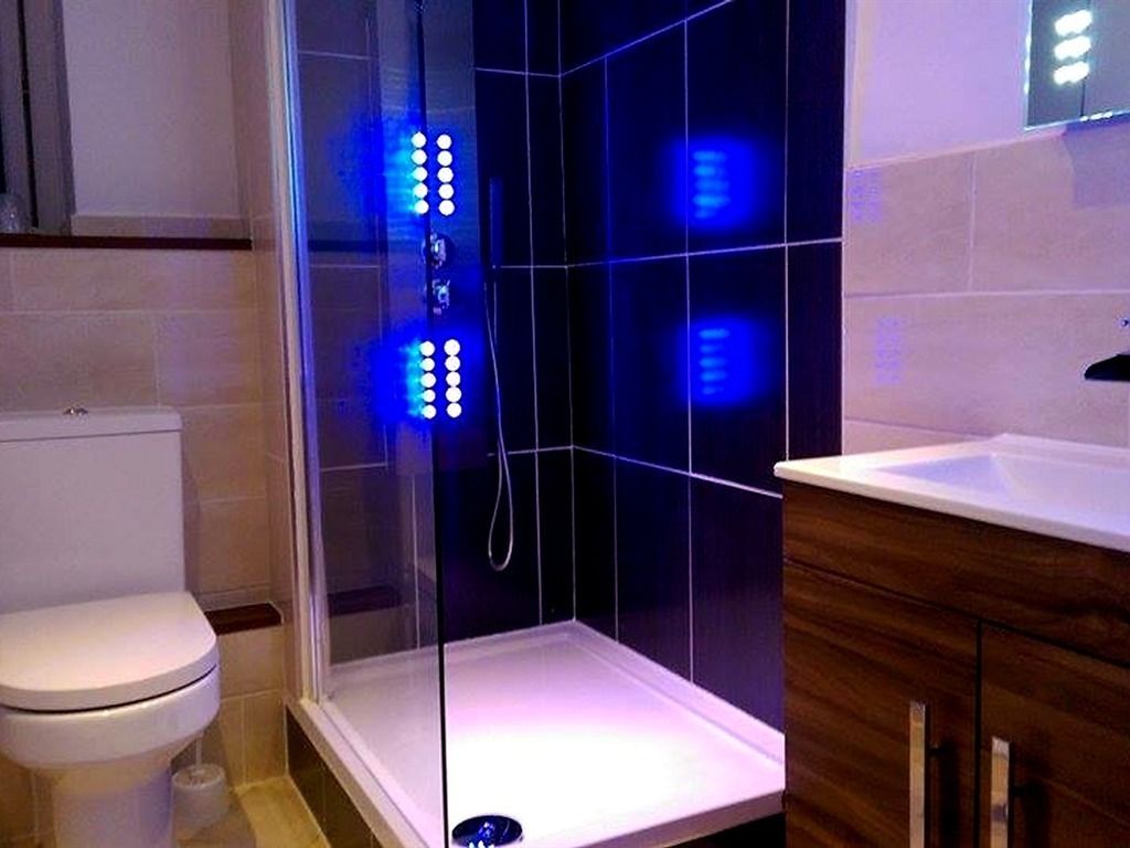 Une salle de bain moderne avec une douche à parois de verre, des toilettes blanches et un meuble-lavabo en bois.