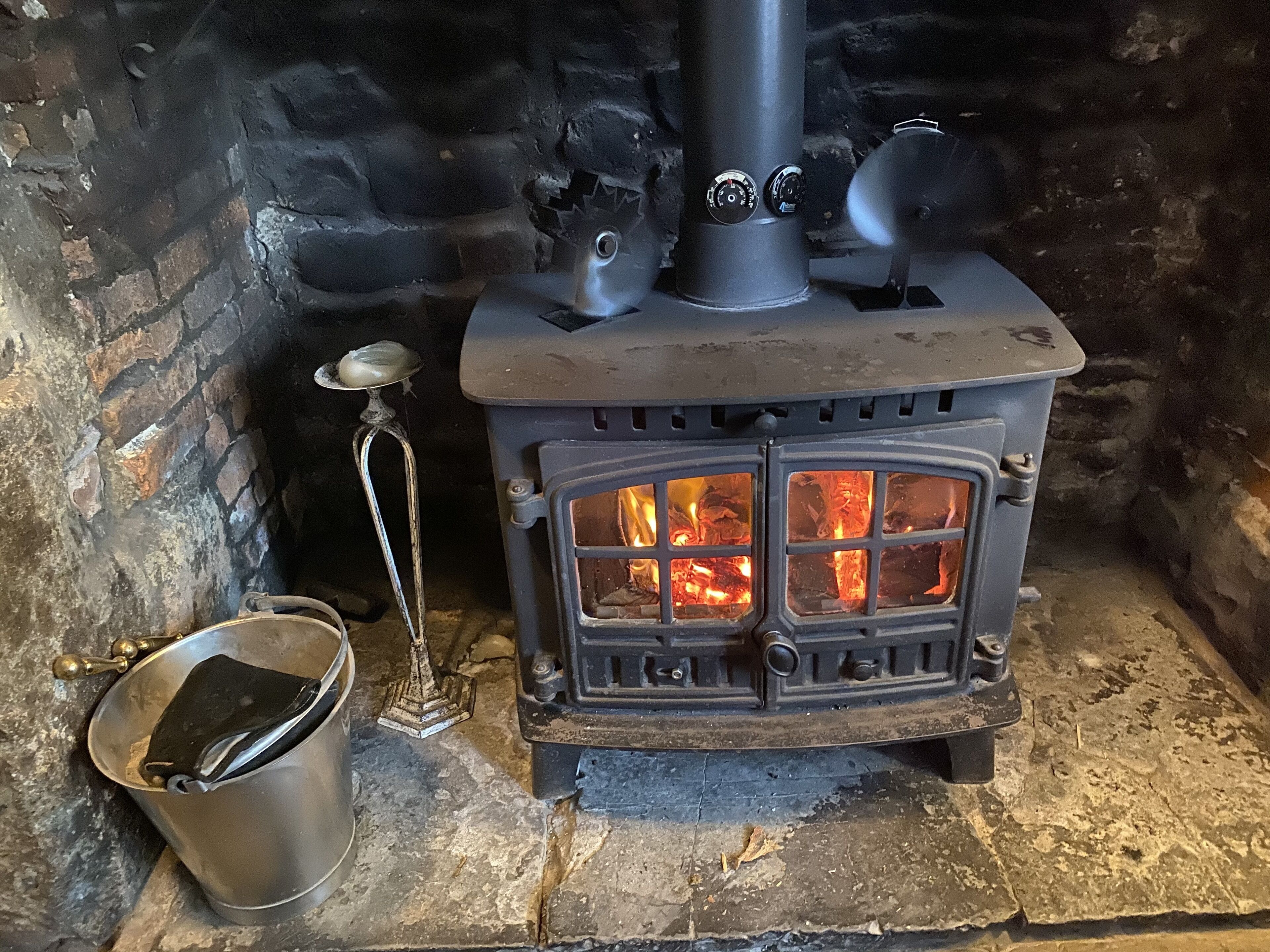 Ein Holzofen mit einem Metallkübel und einem Metallsauger daneben.