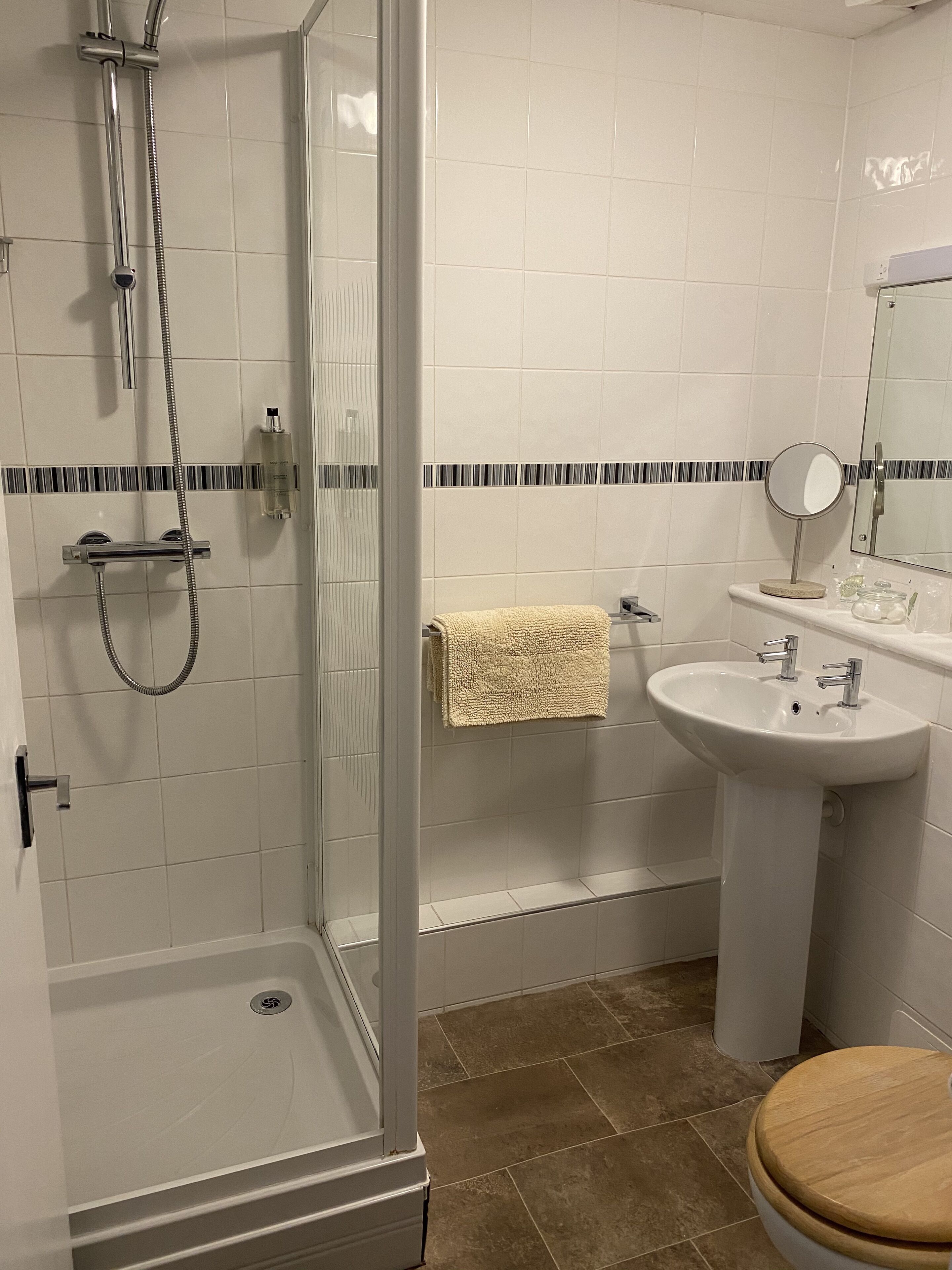 A bathroom with a glass-enclosed shower, a white sink, and a wooden toilet.