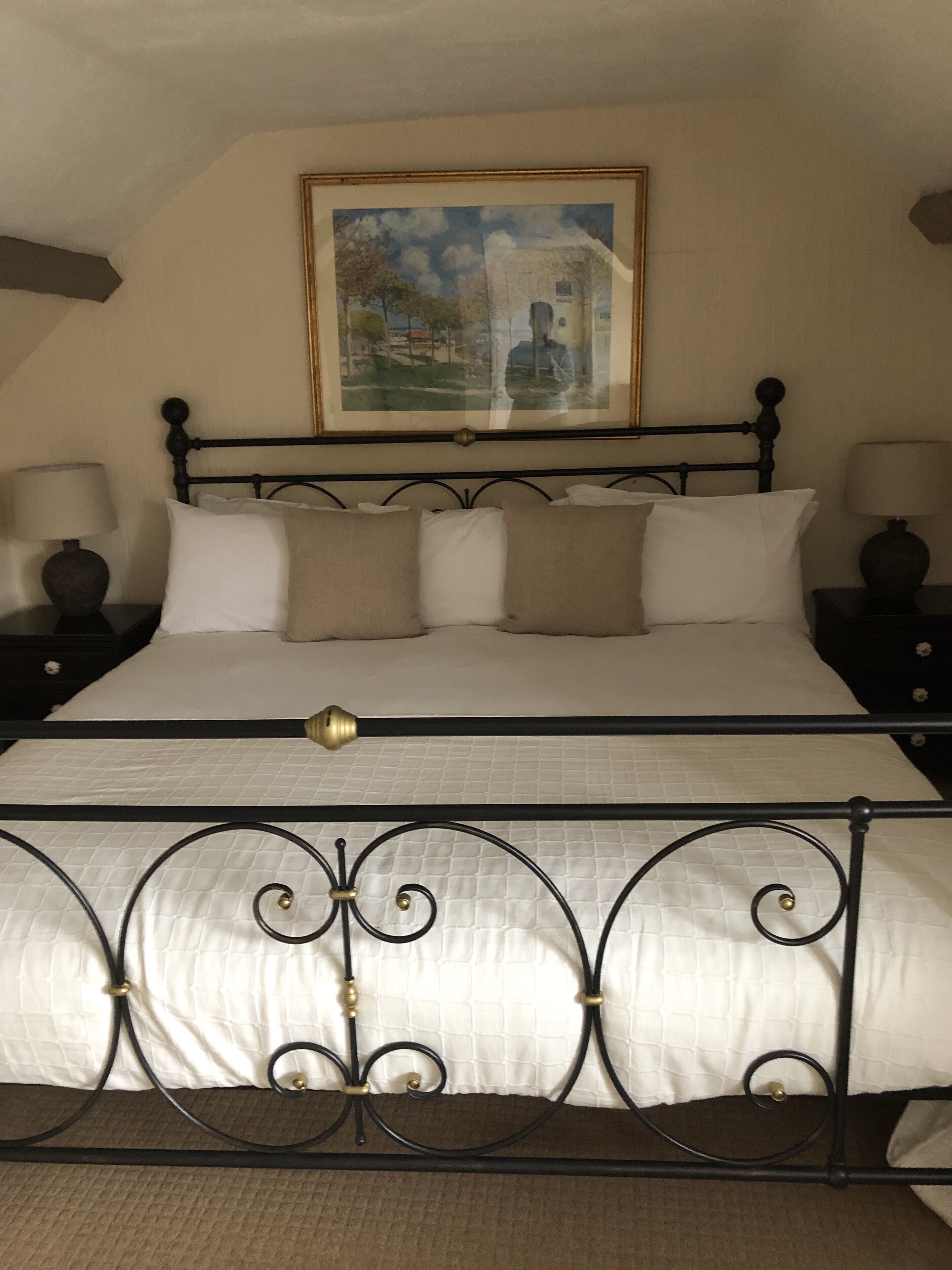 A bed with a metal frame, white bedding, and two bedside tables with lamps.