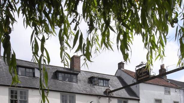 Il s’agit d’un bâtiment traditionnel de couleur blanche, sur lequel on peut lire l’inscription « The George Wadworth ». Il est doté de nombreuses fenêtres et d’une porte noire, et est entouré d’un espace recouvert de gravier, agrémenté de plantes et d’arbustes.