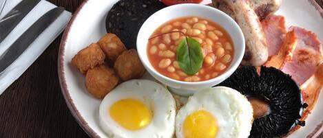 A plate of breakfast food including eggs, beans, sausages, and bacon.