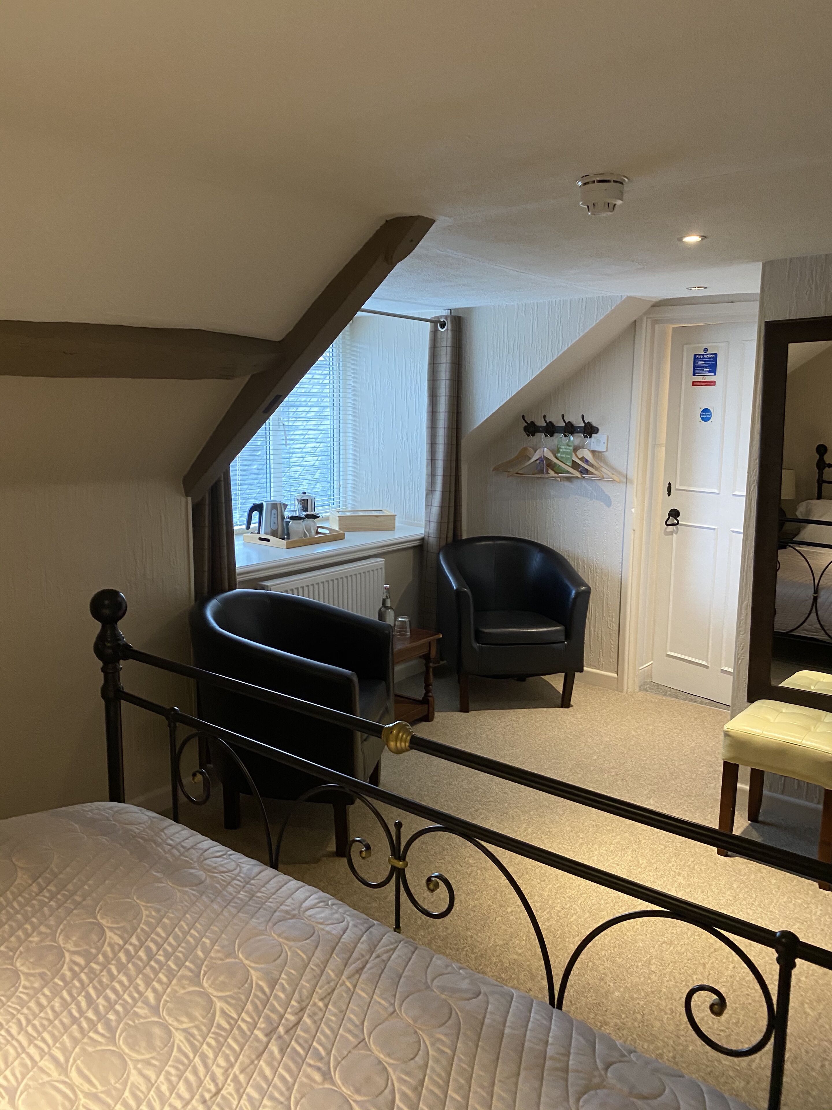A bedroom with a bed, a chair, a small table, and a window with blinds.