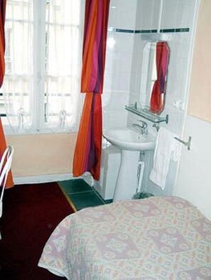 A bathroom with a sink, mirror, and window with curtains. - Hotel de Lille - Louvre (Paris)