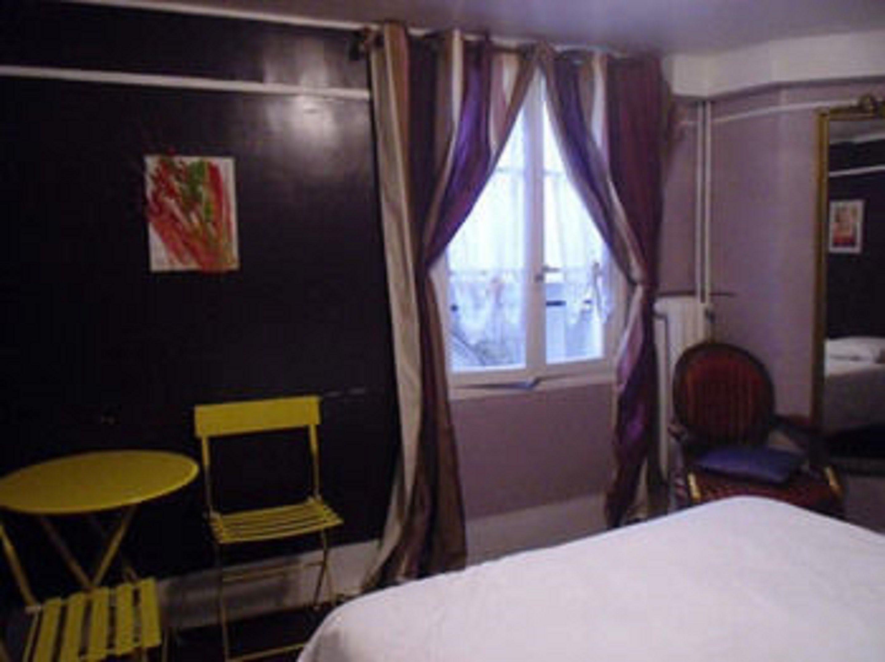 A room with a bed, a small table, a chair, and a window with curtains.