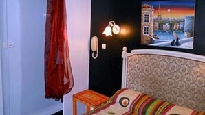 Habitación de hotel con una cama, una mesita, un teléfono y un cuadro en la pared.