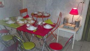 Un comedor con mantel rojo, varias sillas y una mesa pequeña con una lámpara.