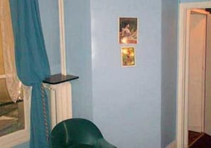 A room with a blue wall, a small table, and two framed pictures. - Hotel de Lille - Louvre (Paris)