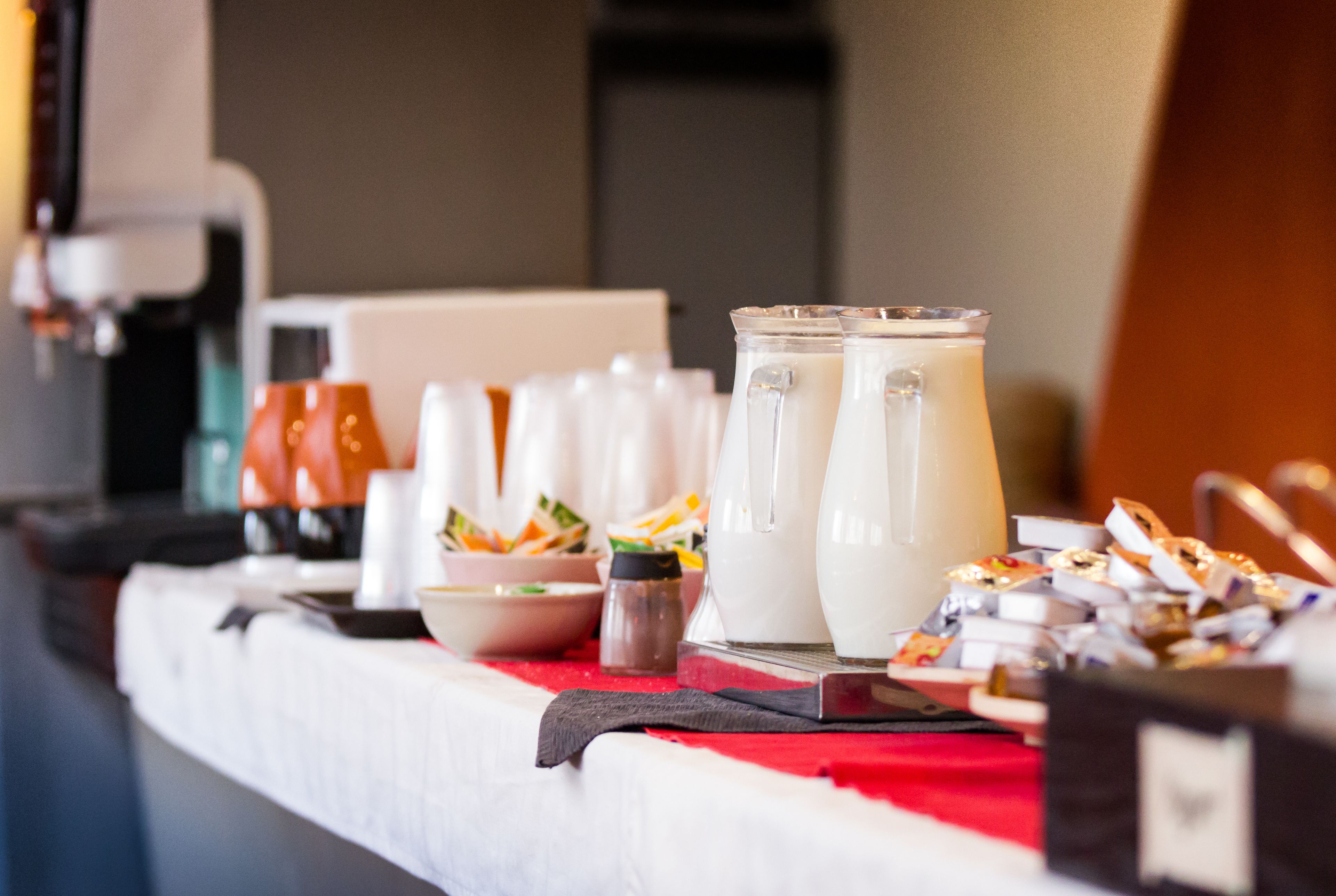 A buffet table with various food items and a pitcher of milk.