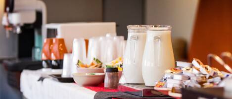 A buffet table with various food items and a pitcher of milk.