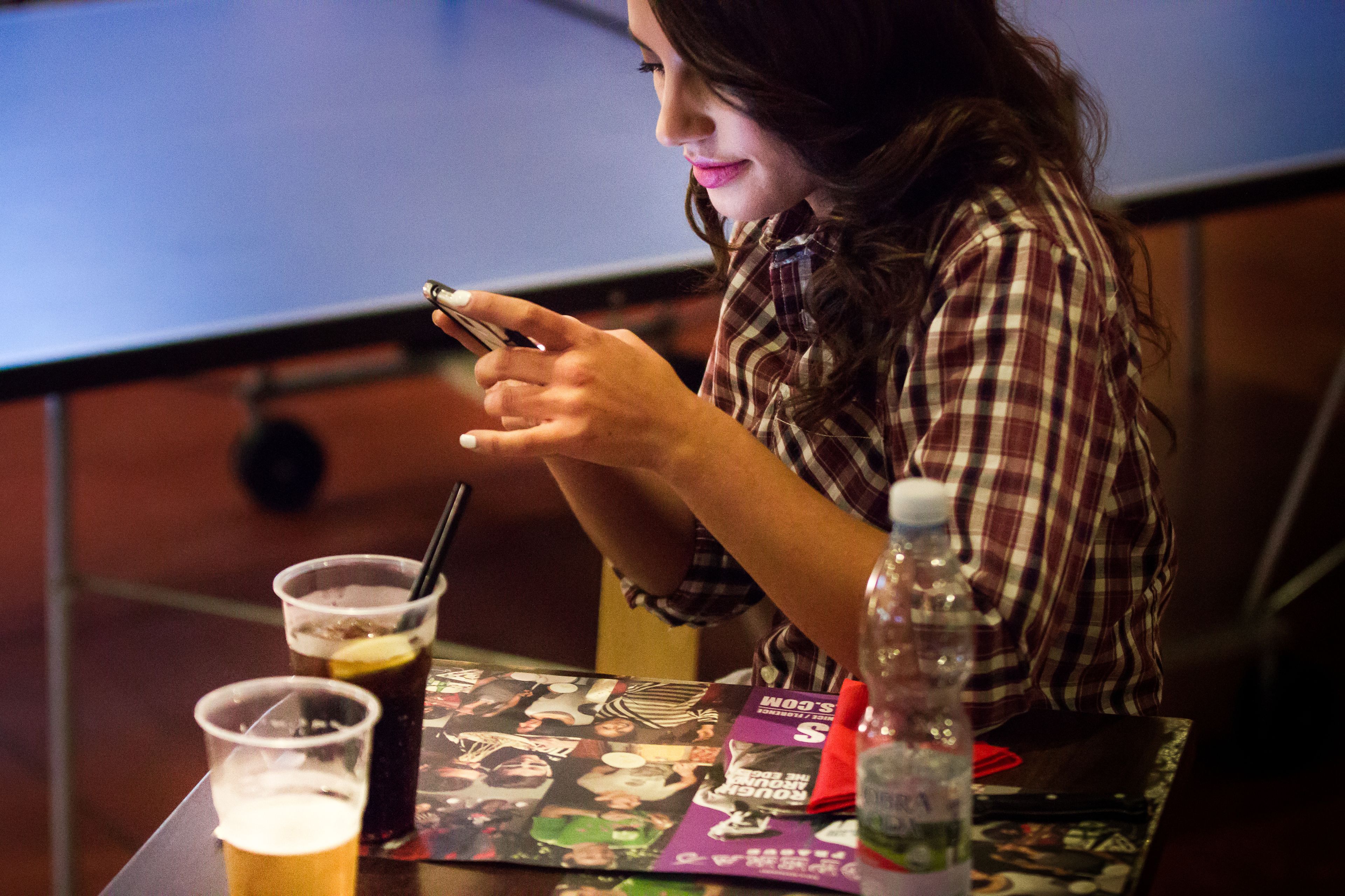A person seated at a table with a beverage and a bottle of water.