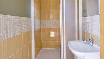 Ein Badezimmer mit Duschkabine, Waschbecken und Spiegel.