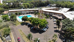 An aerial view of a hotel with a swimming pool, parking lot, and surrounding greenery. - Dom Pedro I Palace Hotel (Foz do Iguaçu)