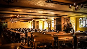 A restaurant with multiple tables and chairs, chandeliers, and a large window with natural light. - Dom Pedro I Palace Hotel (Foz do Iguaçu)