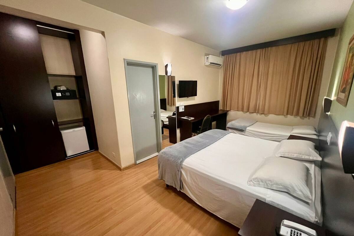 Une chambre d’hôtel avec deux lits, un bureau, une chaise, une télévision et un appareil de climatisation.