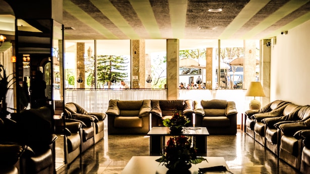 A lobby with leather sofas, a coffee table, and large windows with views of outdoor seating. - Dom Pedro I Palace Hotel (Foz do Iguaçu)