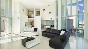 Un amplio salón con un sofá blanco, un sofá de cuero negro y una mesa de centro.