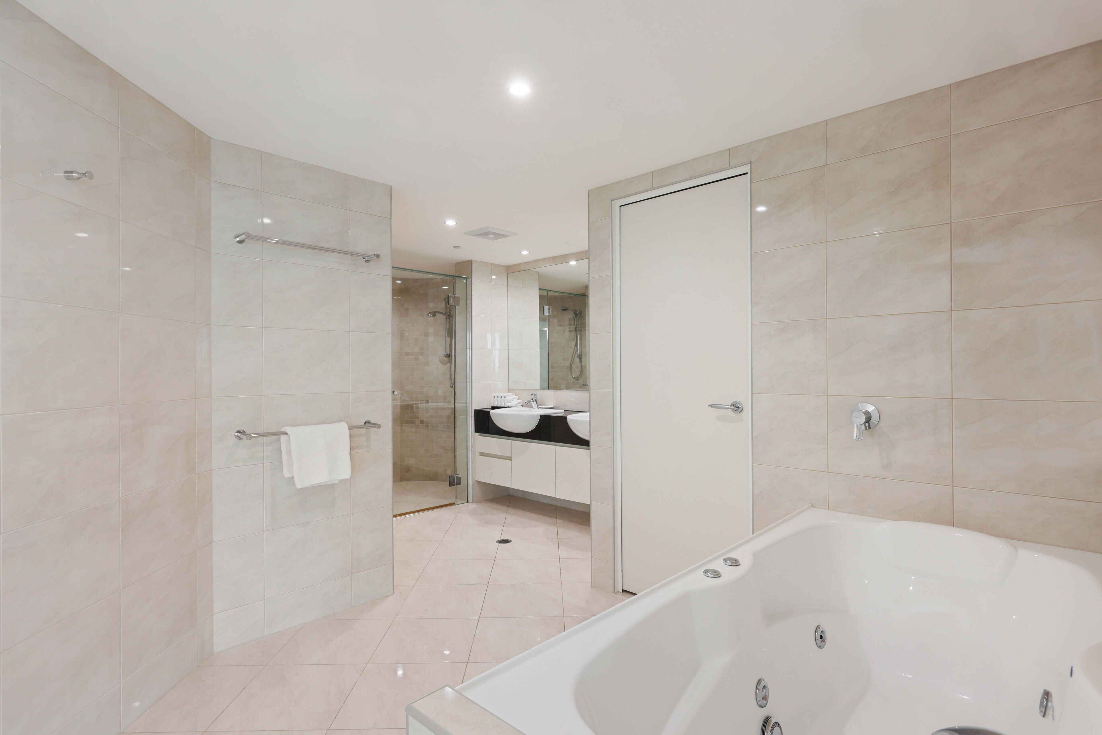 Un baño moderno con ducha a ras de suelo, bañera y tocador con espejo.