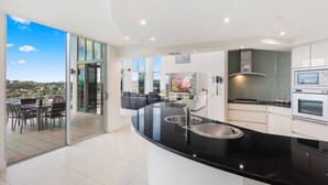 Una cocina moderna con encimera negra, pileta de acero inoxidable y muebles blancos.