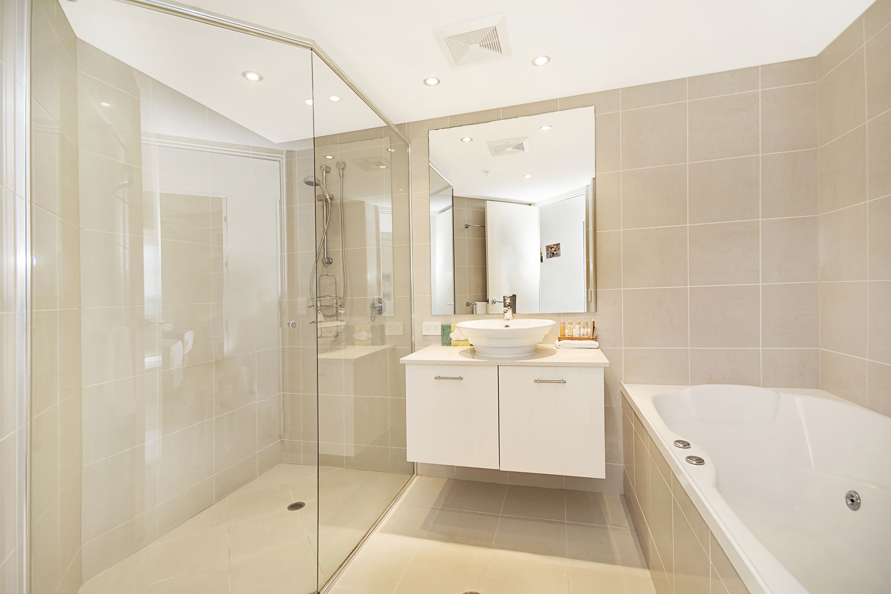 Un baño moderno con ducha de vidrio, tocador blanco con lavamanos y bañera independiente.