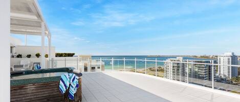 A rooftop terrace with a view of the sea and buildings.
