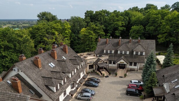 A traditional European-style building with a courtyard, multiple cars parked, and surrounding greenery. - Sarmata (Sandomierz)