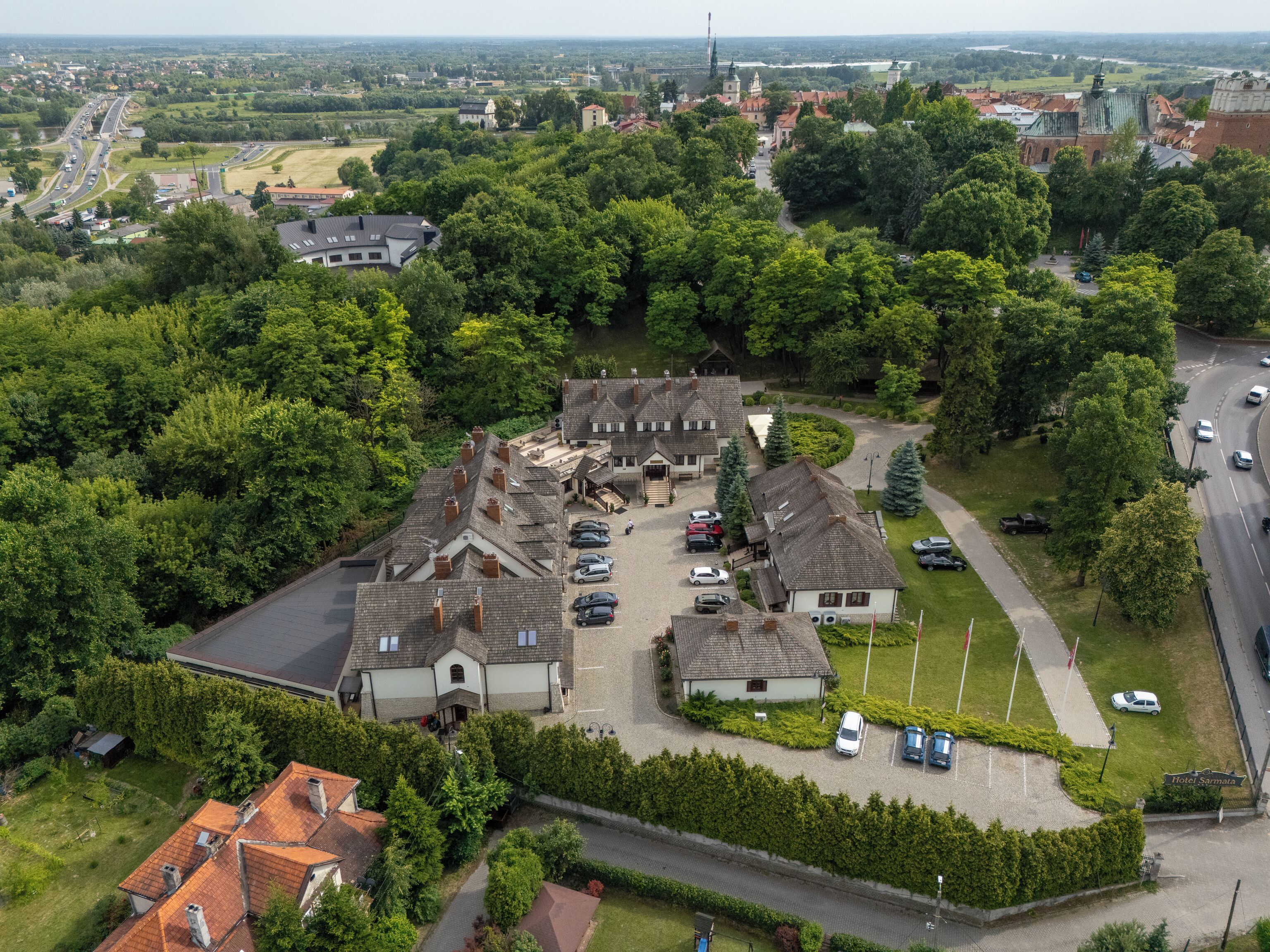 An aerial view of a hotel with multiple buildings, parking areas, and surrounding greenery.